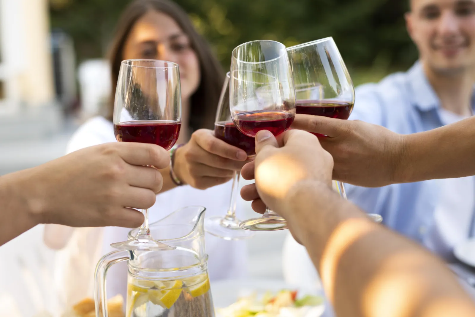 Friends clinking glasses of red wine at an outdoor table