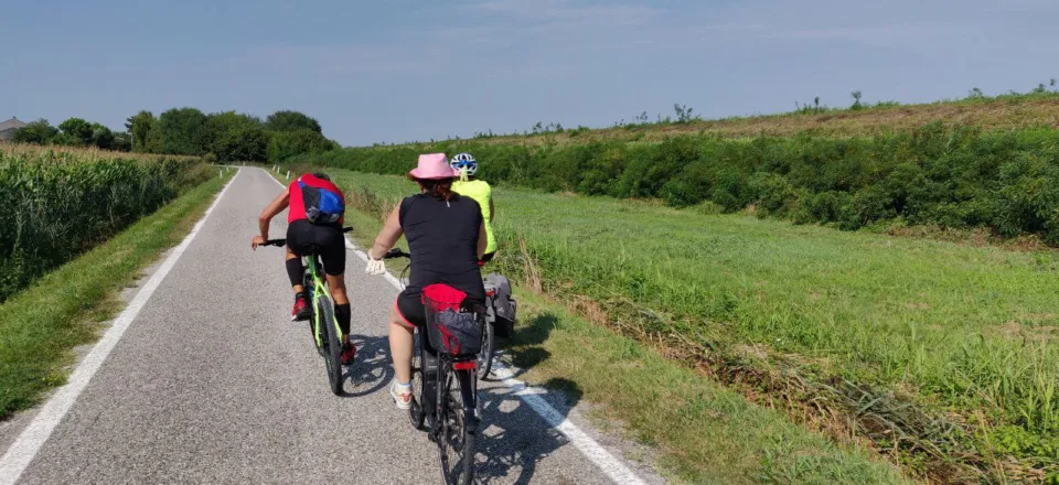 Two cyclists on a flat bike path through green countryside