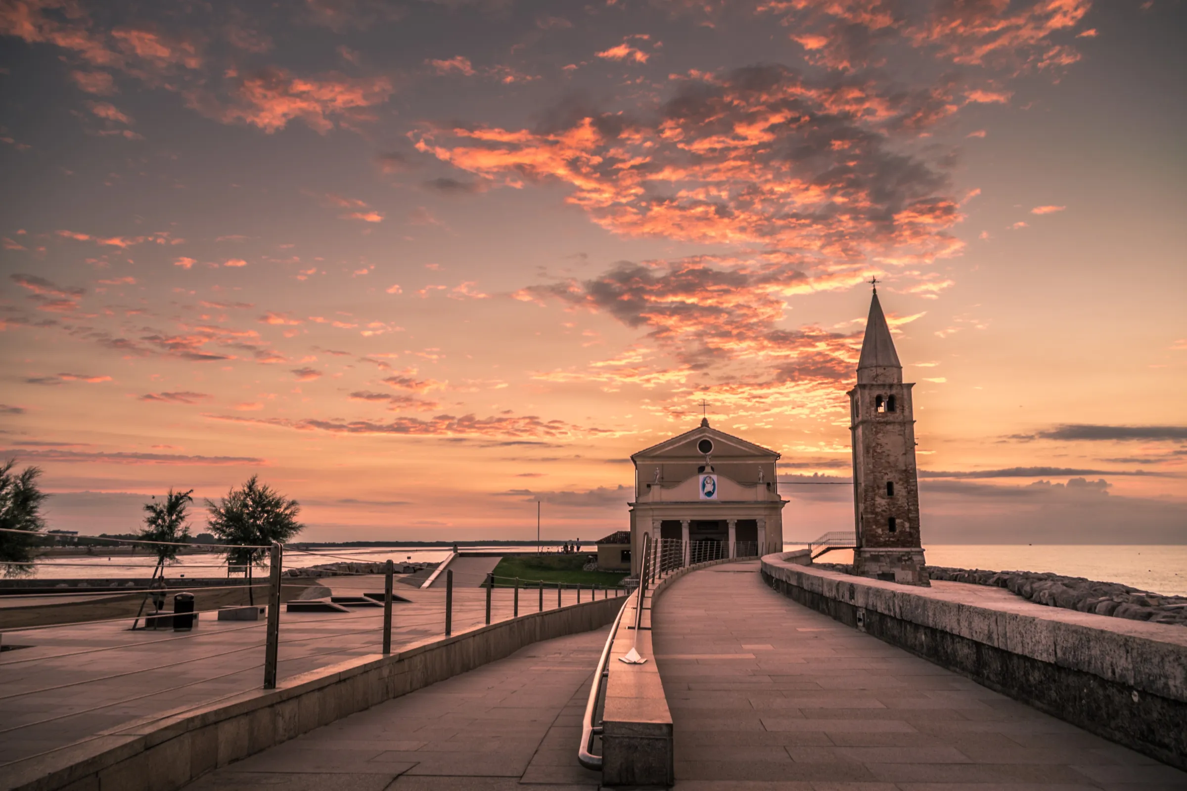 Madonna dell'Angelo sanctuary on the seafront of Caorle under a pink sunset sky
