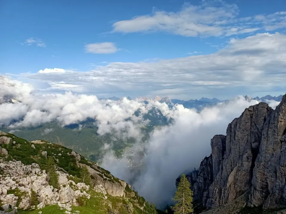Sea of clouds filling a Dolomite valley below a rocky ridge