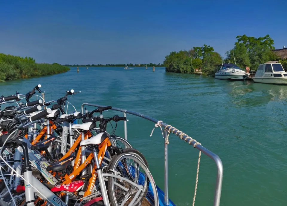 Bicycles loaded on a boat cruising through a turquoise lagoon channel