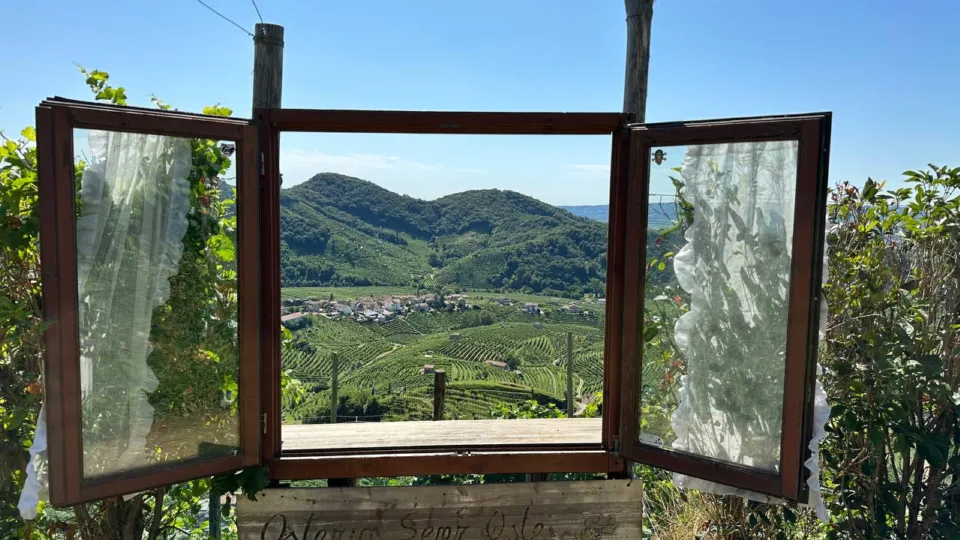Old wooden window frame opening onto the Prosecco vineyards